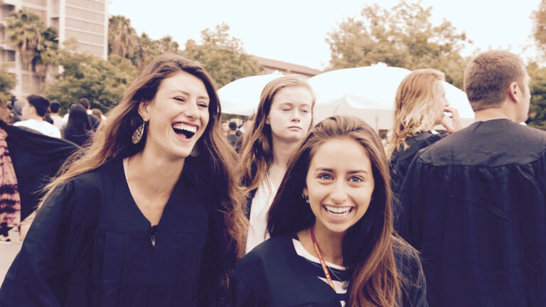 Two students smiling and laughing at Commencement.