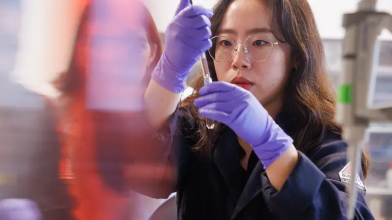 Student working in a Chemistry lab focusing on inserting liquid into a vial.