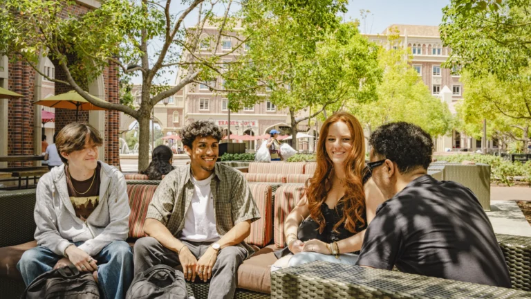 Four students sitting and talking outdoors.
